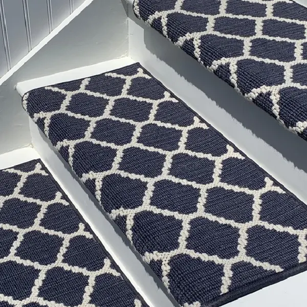 Navy blue trellis marine carpet runners installed on white wooden stairs.